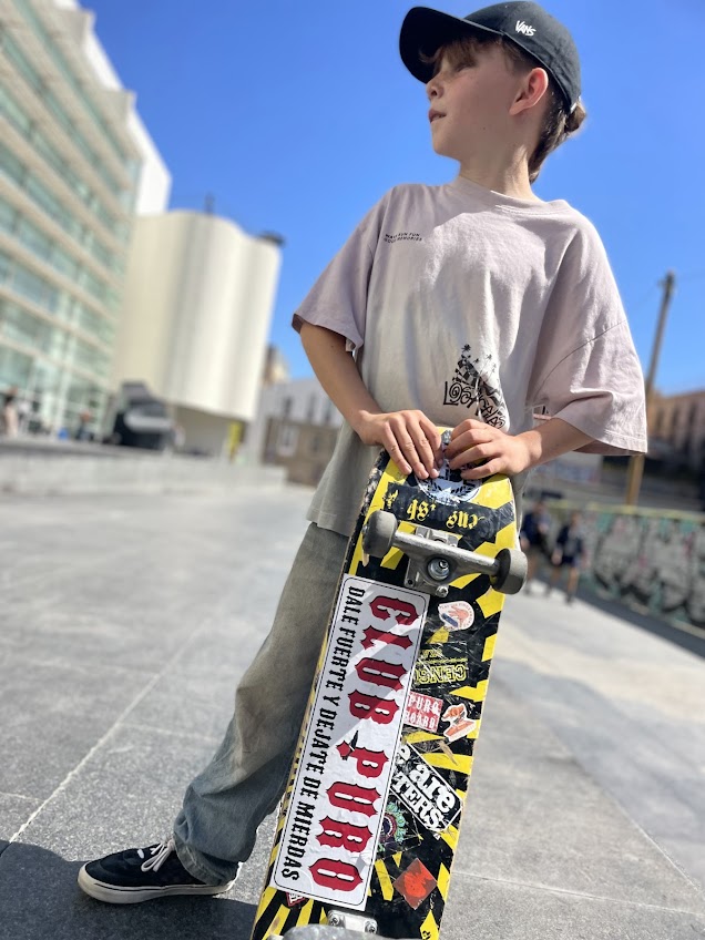 Standing with a sticker-covered skateboard